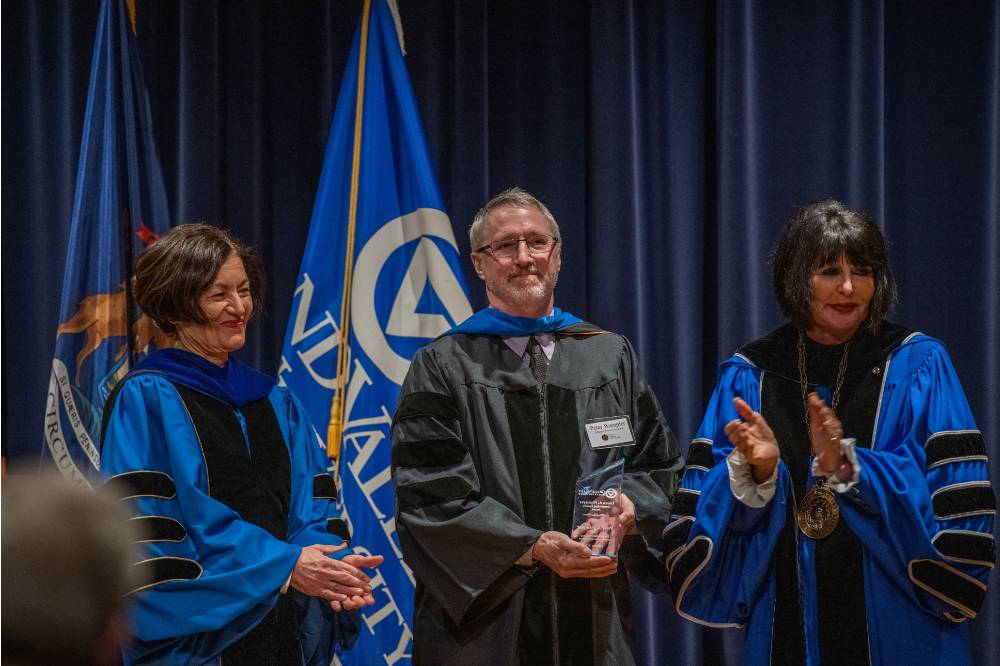 Provost and President applaud with man on stage